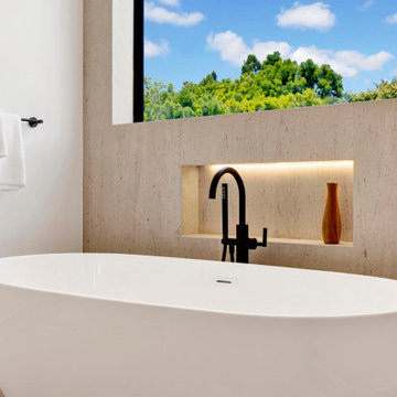 Freestanding soaking tub with a lit stone niche