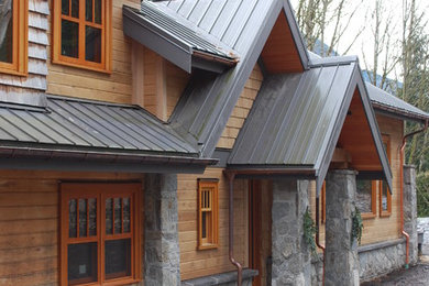 Inspiration for a large arts and crafts two-storey brown house exterior in Vancouver with wood siding, a gable roof and a metal roof.