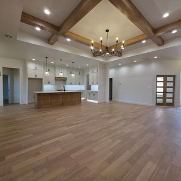 Open concept with hardwood floors, custom cabinets, beamed tray ceilings and rec