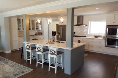 Example of a large transitional dark wood floor and brown floor open concept kitchen design in Toronto with an undermount sink, shaker cabinets, white cabinets, quartz countertops, white backsplash, ceramic backsplash, stainless steel appliances and an island