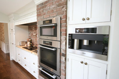 Mid-sized elegant single-wall medium tone wood floor eat-in kitchen photo in Seattle with a double-bowl sink, white cabinets, granite countertops, beige backsplash, stainless steel appliances, an island, recessed-panel cabinets and brick backsplash