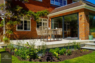 Diseño de jardín de tamaño medio en verano en patio trasero con jardín francés, parterre de flores, exposición total al sol y entablado