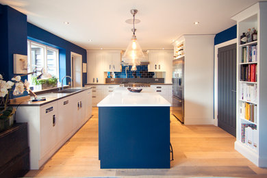 Inspiration for a transitional u-shaped kitchen in Other with an undermount sink, flat-panel cabinets, white cabinets, blue splashback, subway tile splashback, light hardwood floors and with island.
