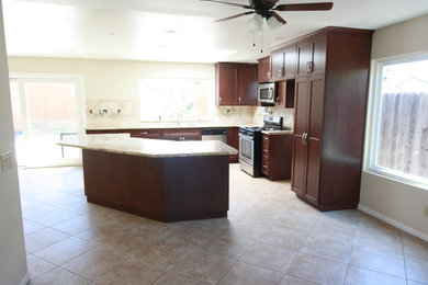 Arts and crafts l-shaped terra-cotta tile eat-in kitchen photo in Los Angeles with an undermount sink, shaker cabinets, dark wood cabinets, laminate countertops, blue backsplash, stone tile backsplash, stainless steel appliances and an island
