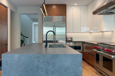 Inspiration for an expansive modern l-shaped kitchen/diner in San Francisco with a submerged sink, flat-panel cabinets, medium wood cabinets, composite countertops, white splashback, stone slab splashback, stainless steel appliances, light hardwood flooring, an island and grey worktops.