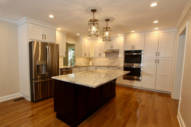 Large elegant l-shaped light wood floor and brown floor open concept kitchen photo in Baltimore with an undermount sink, raised-panel cabinets, white cabinets, granite countertops, white backsplash, ceramic backsplash, stainless steel appliances, an island and gray countertops