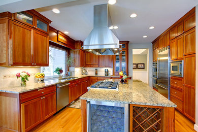 Medium tone wood floor kitchen photo in Louisville with raised-panel cabinets, medium tone wood cabinets, granite countertops, stainless steel appliances and an island
