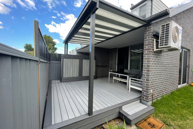 This is an example of a mid-sized backyard and ground level deck in Sydney with a pergola.
