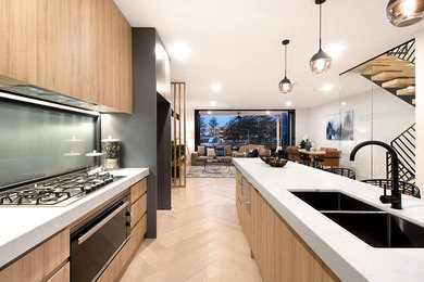 Mid-sized contemporary galley eat-in kitchen in Gold Coast - Tweed with an undermount sink, flat-panel cabinets, grey cabinets, quartz benchtops, blue splashback, black appliances, light hardwood floors, with island and white benchtop.