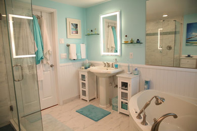 Photo of a large traditional master bathroom in Other with furniture-like cabinets, white cabinets, a freestanding tub, a corner shower, a one-piece toilet, white tile, marble, blue walls, marble floors, a pedestal sink, solid surface benchtops, white floor and a hinged shower door.