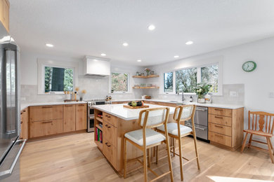 Inspiration for a huge scandinavian u-shaped light wood floor and brown floor eat-in kitchen remodel in Portland with a drop-in sink, flat-panel cabinets, light wood cabinets, quartz countertops, white backsplash, ceramic backsplash, stainless steel appliances, an island and white countertops