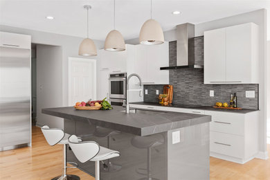 Eat-in kitchen - large contemporary l-shaped light wood floor eat-in kitchen idea in DC Metro with an undermount sink, flat-panel cabinets, white cabinets, granite countertops, black backsplash, ceramic backsplash, stainless steel appliances, an island and black countertops