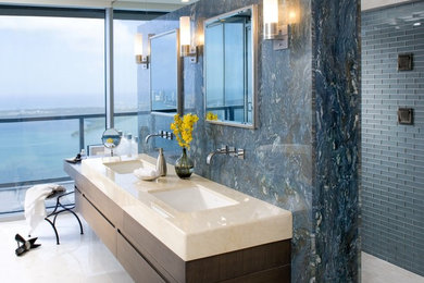 This is an example of a mid-sized contemporary master bathroom in Miami with flat-panel cabinets, dark wood cabinets, an open shower, a one-piece toilet, blue tile, glass tile, blue walls, marble floors, an undermount sink and limestone benchtops.