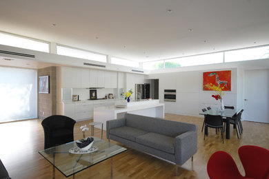 Example of a minimalist light wood floor eat-in kitchen design in Phoenix with flat-panel cabinets, white cabinets, quartz countertops, stainless steel appliances and an island