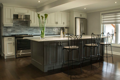 Example of a large classic l-shaped enclosed kitchen design in Toronto with an undermount sink, beige cabinets, granite countertops, beige backsplash, stainless steel appliances, an island and raised-panel cabinets