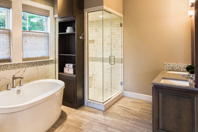Mid-sized transitional master white tile and marble tile porcelain tile and brown floor bathroom photo in Other with raised-panel cabinets, medium tone wood cabinets, brown walls, an undermount sink, solid surface countertops, a hinged shower door and gray countertops