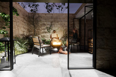 Inspiration for a small modern courtyard patio remodel in Other with a fire pit