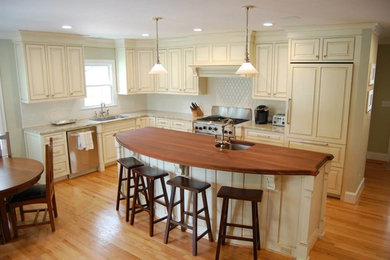 Inspiration for a mid-sized timeless l-shaped light wood floor and beige floor open concept kitchen remodel in Charlotte with an undermount sink, beaded inset cabinets, white cabinets, granite countertops, white backsplash, ceramic backsplash, stainless steel appliances and an island