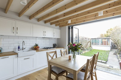 Immagine di una cucina minimal di medie dimensioni con lavello stile country, ante con riquadro incassato, ante bianche, pavimento in legno massello medio e pavimento marrone
