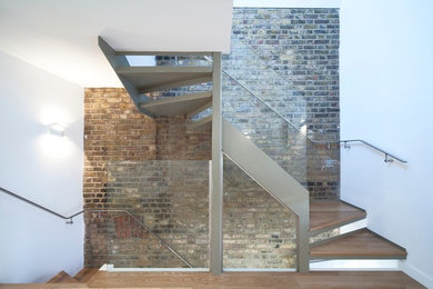 Mid-sized contemporary wood u-shaped staircase in London with metal risers.