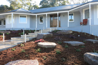 Large traditional front partial sun garden in Melbourne with a garden path and natural stone paving.