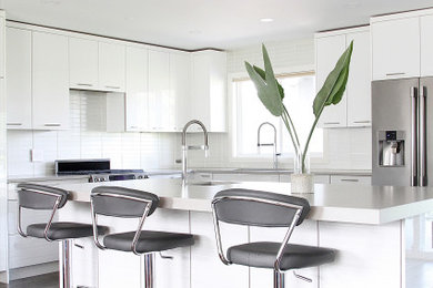 Example of a mid-century modern l-shaped vinyl floor and gray floor eat-in kitchen design in Vancouver with an undermount sink, flat-panel cabinets, white cabinets, quartz countertops, white backsplash, glass tile backsplash, stainless steel appliances, an island and gray countertops