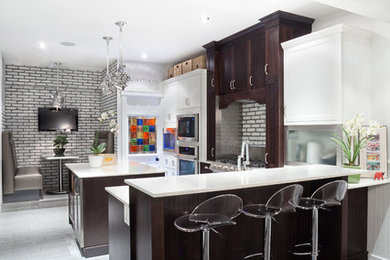 Mid-sized trendy l-shaped medium tone wood floor eat-in kitchen photo in Edmonton with recessed-panel cabinets, dark wood cabinets, quartz countertops, gray backsplash, brick backsplash, stainless steel appliances and an island