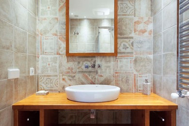 Design ideas for a small country powder room in Valencia with open cabinets, dark wood cabinets, a one-piece toilet, multi-coloured tile, ceramic tile, multi-coloured walls, ceramic floors, a vessel sink, wood benchtops and brown floor.