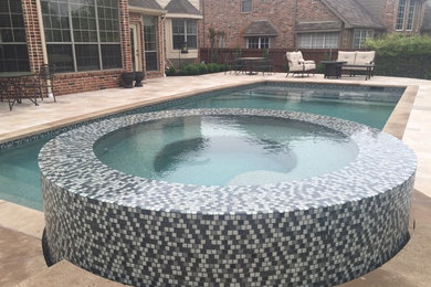 This is an example of a mid-sized contemporary backyard custom-shaped natural pool in Dallas with a hot tub and natural stone pavers.