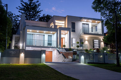 This is an example of a large contemporary front yard driveway in Sydney with a retaining wall.