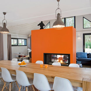 На фото: большая гостиная-столовая в современном стиле с оранжевыми стенами и светлым паркетным полом с