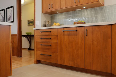Inspiration for a mid-sized 1960s l-shaped porcelain tile eat-in kitchen remodel in Los Angeles with a double-bowl sink, flat-panel cabinets, medium tone wood cabinets, quartz countertops, gray backsplash, glass tile backsplash, paneled appliances and a peninsula