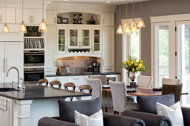 Example of a large transitional l-shaped dark wood floor eat-in kitchen design in Minneapolis with an undermount sink, recessed-panel cabinets, white cabinets, granite countertops, gray backsplash, stone tile backsplash, stainless steel appliances and an island