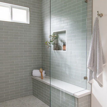 The completely remodeled walk-in shower walls are lined in matte gray-green subw