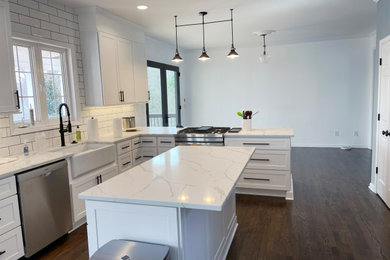Large minimalist dark wood floor eat-in kitchen photo in Raleigh with a farmhouse sink, shaker cabinets, white cabinets, quartz countertops, stainless steel appliances and an island