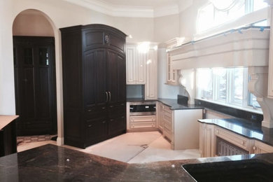 Inspiration for a 1950s marble floor kitchen remodel in Denver with white cabinets, granite countertops and black appliances