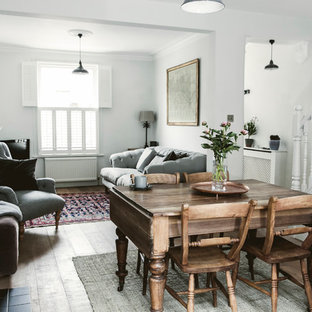 Inredning av en lantlig matplats, med vita väggar, mellanmörkt trägolv, en standard öppen spis och brunt golv