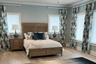 Modelo de habitación de invitados costera extra grande con paredes verdes y suelo de madera en tonos medios
