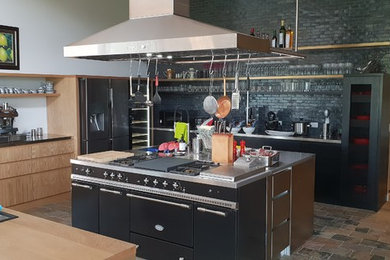 This is an example of a large contemporary kitchen in Melbourne with an integrated sink, flat-panel cabinets, stainless steel benchtops, ceramic splashback, stainless steel appliances, slate floors, multiple islands and multi-coloured floor.