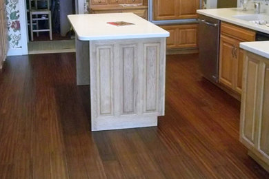 Mid-sized elegant vinyl floor and brown floor kitchen photo in Chicago with an integrated sink, raised-panel cabinets, light wood cabinets, paneled appliances and an island