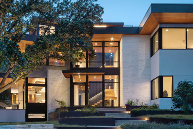 Trendy white two-story exterior home photo in Austin with a mixed material roof and a black roof