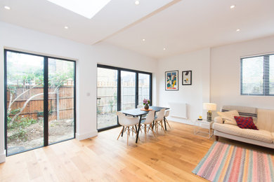Example of a huge trendy light wood floor and brown floor great room design in Surrey with white walls