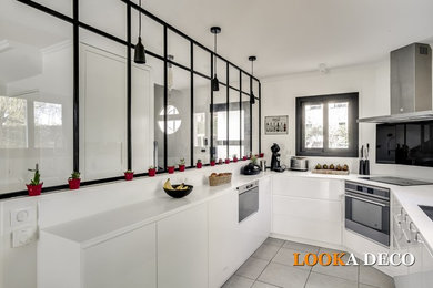 パリにあるお手頃価格の中くらいなコンテンポラリースタイルのおしゃれなキッチン (セラミックタイルの床、グレーの床、アンダーカウンターシンク、白いキャビネット、大理石カウンター、白いキッチンパネル、パネルと同色の調理設備、白いキッチンカウンター) の写真