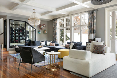 Ejemplo de sala de estar abierta clásica renovada grande con paredes grises, suelo de madera en tonos medios, televisor colgado en la pared, suelo marrón y casetón