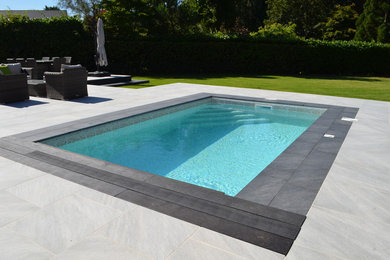 Photo of a small modern back rectangular swimming pool in West Midlands with natural stone paving.