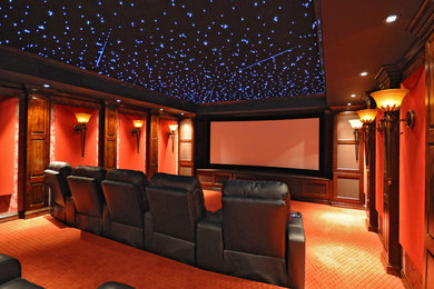 Design ideas for a mid-sized traditional enclosed home theatre in Milwaukee with red walls, carpet, a projector screen and orange floor.