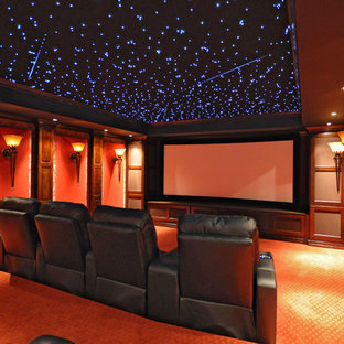 Exemple d'une salle de cinéma chic de taille moyenne et fermée avec un mur rouge, moquette, un écran de projection et un sol orange.