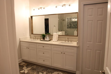 Photo of a mid-sized arts and crafts master bathroom in Tampa with shaker cabinets, white cabinets, a curbless shower, a two-piece toilet, white tile, porcelain tile, white walls, porcelain floors, an undermount sink, engineered quartz benchtops, brown floor and a hinged shower door.