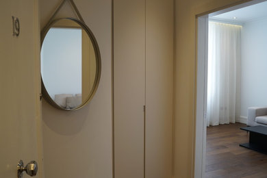 Design ideas for a medium sized contemporary hallway in London with white walls, dark hardwood flooring, a single front door, a white front door and brown floors.