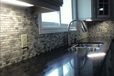 This is an example of a traditional eat-in kitchen in Toronto with multi-coloured splashback and stone tile splashback.